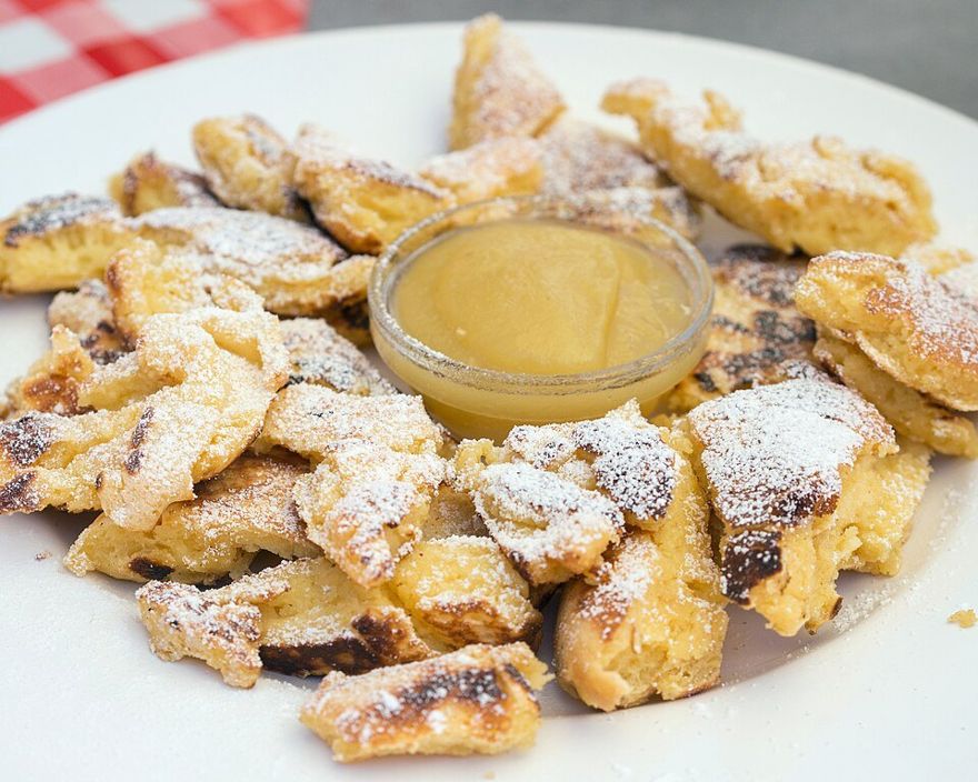 Torn, caramelised Kaiserschmarrn dusted with icing sugar, served with apple sauce